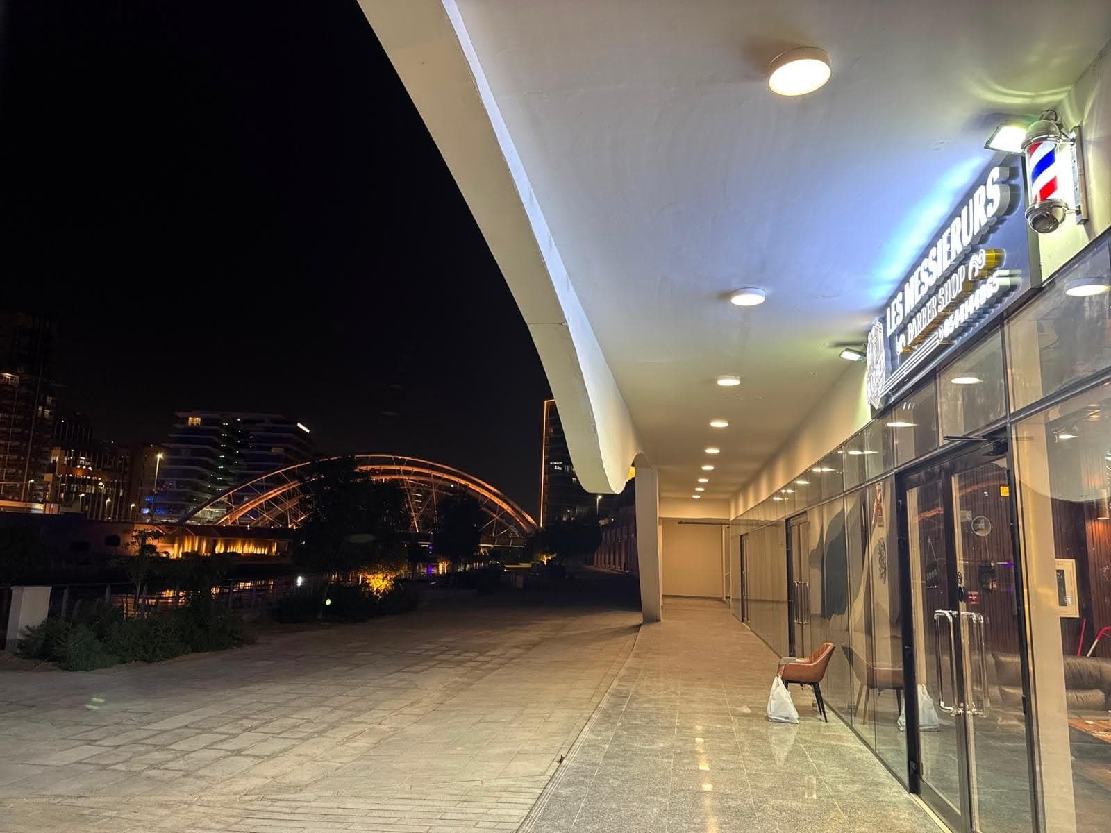 The covered promenade outside the shop, with a lit arch bridge over the water
