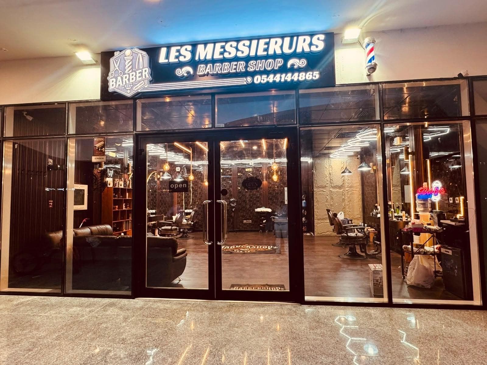 The lit Les Messieurs storefront at night